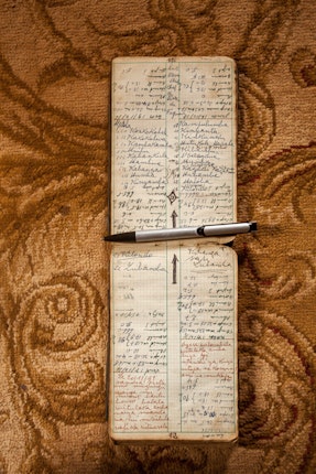 The notebook of Sanga Chief Mpala Swanage Pascal Musenge, shown in 2013, contains a list of the names of all his predecessors. Photo credit: © Sammy Baloji A notebook and pen