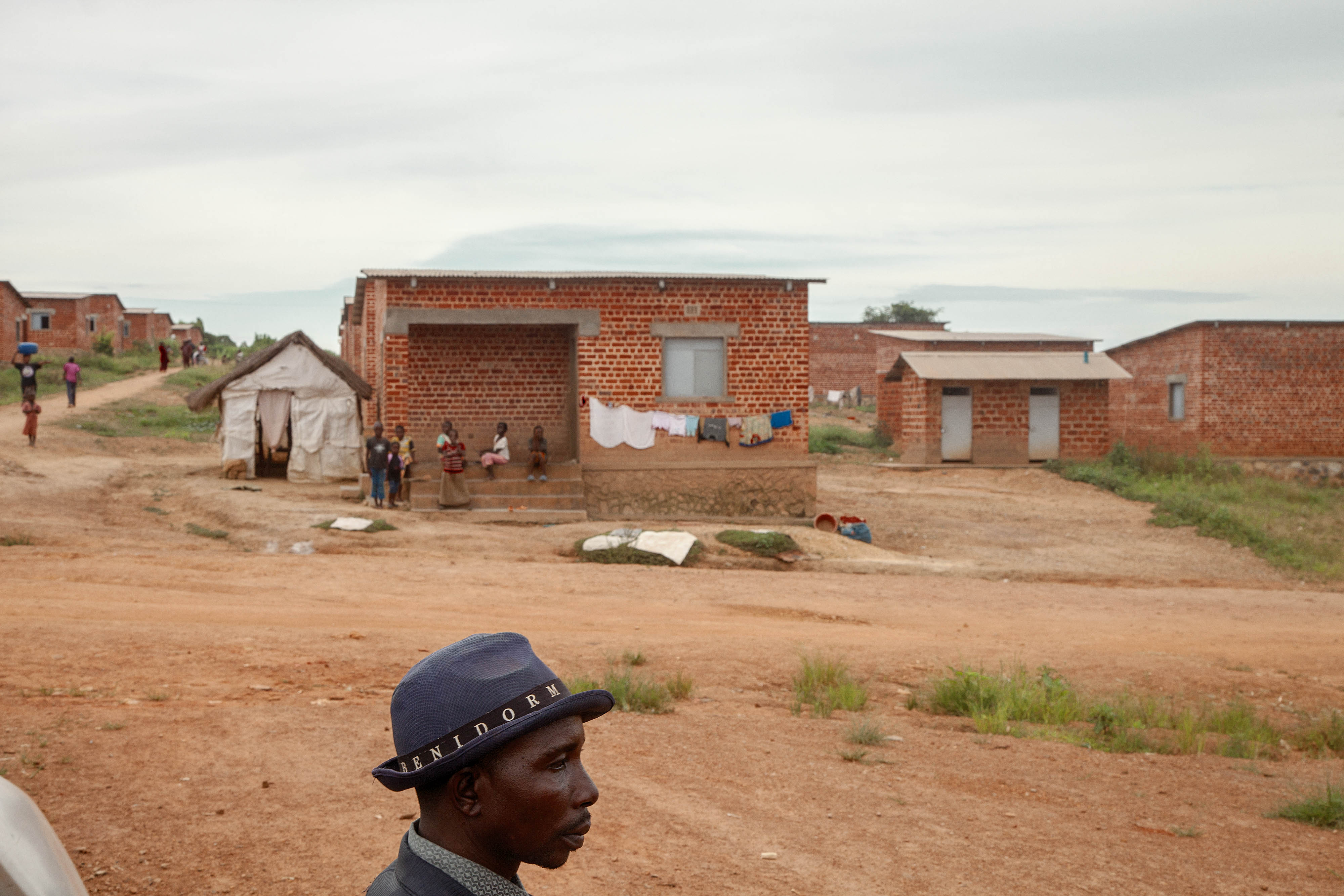 A man wearing a hat in front of houses