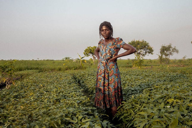 A horticulturalist stands in the Malebo Pool gardens in 2013. Since the end of the colonial period, the south of the Malebo Pool—a lakelike expansion of the lower Congo River between the Democratic Republic of Congo and the Republic of the Congo—has steadily transformed into a vast agricultural zone. In the 1980s, a South Korean agricultural company started to develop rice paddies there, but the project was abandoned after widespread looting hit Kinshasa in 1991 and 1993. After the Korean company left, local residents quickly moved in to occupy the rice fields. Before long, they started to expand them, often using shovels or bare hands to fill in and reclaim the pool’s marshes. A large portion of this vast agricultural space will now have to make way for the development of a new satellite city, the Cité du Fleuve, a private development that started in 2008. Photo credit: © Sammy Baloji A woman standing in a field