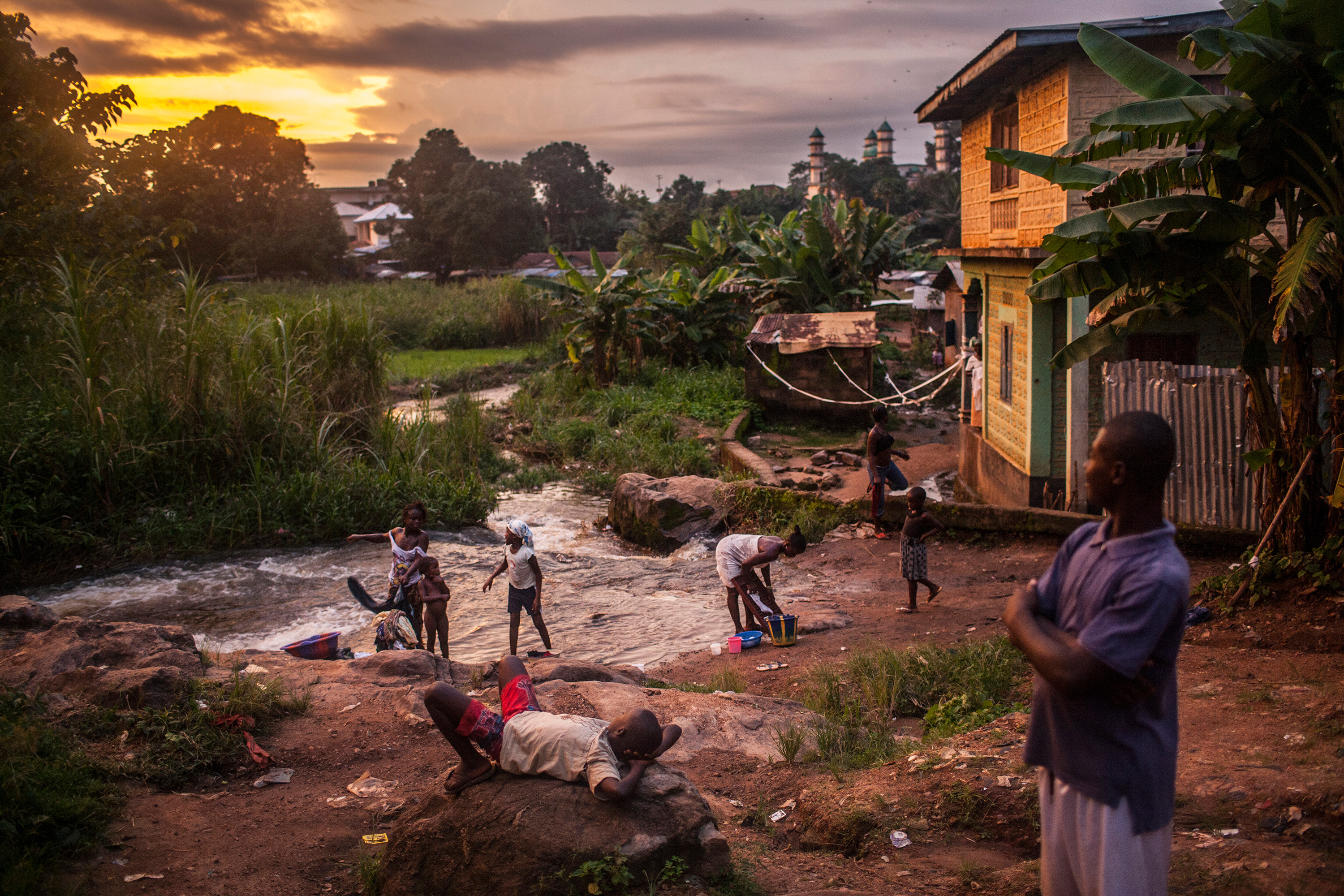 People along a river at sunset