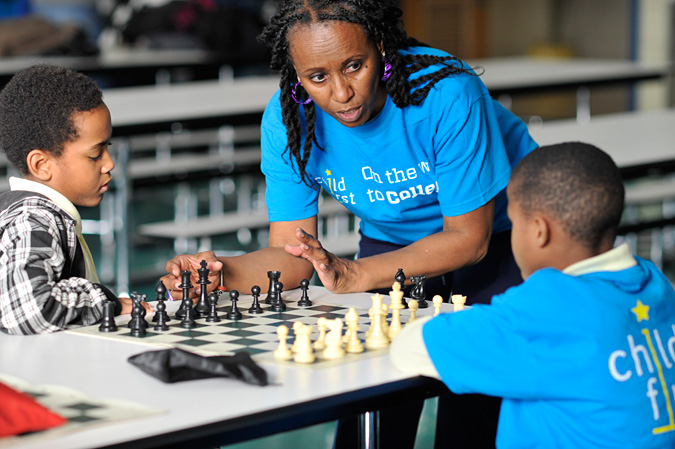 A teacher talking to kids playing chess