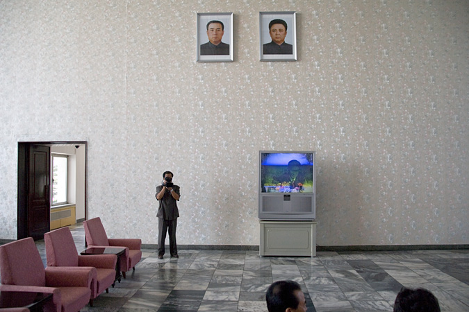 Man with video camera in large room with television