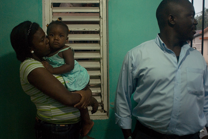 Woman holding child, standing next to man