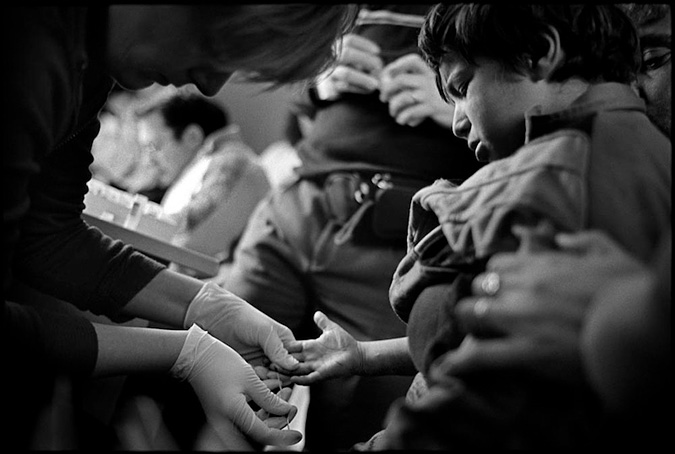 Woman taking a blood sample from a boy.