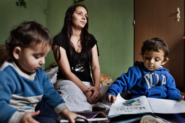 Veronika, photographed at home with her young children in 2012, was one of 18 Roma students represented in the D.H. and Others v. Czech Republic lawsuit that, in 2007, ruled there was a pattern of racial segregation in school admissions that violated nondiscrimination protections.  
Stephanie Sinclair for the Open Society Foundations Woman seated on floor next to two children