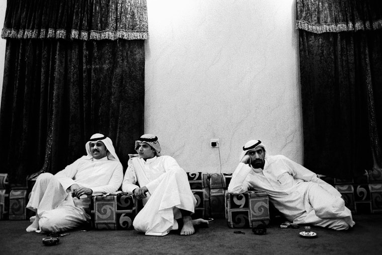 Three men seated outside of building