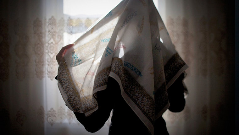 Seda Makhagieva, 15, wraps a pastel-colored head and neck covering around her head. Makhagieva fought to wear the hijab—a sharp break from her family’s traditions. Photo credit: © Diana Markosian/Reportage by Getty Images A young woman with her face covered
