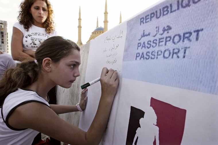 A young woman writing on a large sign in front of a mosque