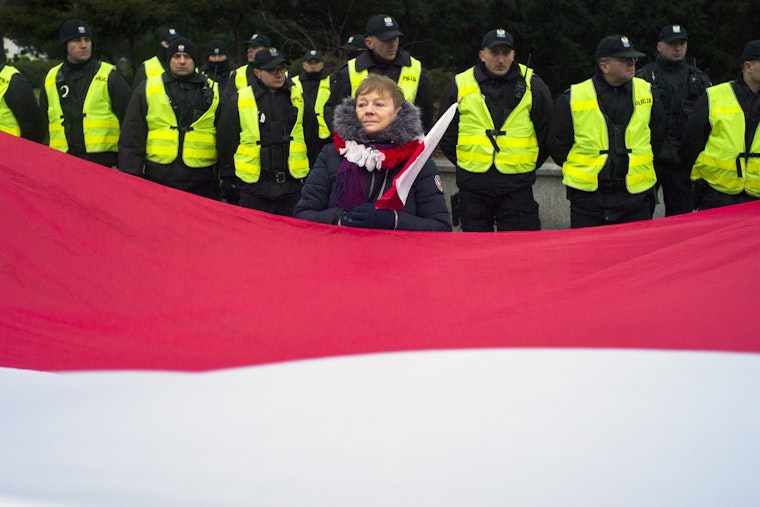 A large Polish flag in front of a row of police