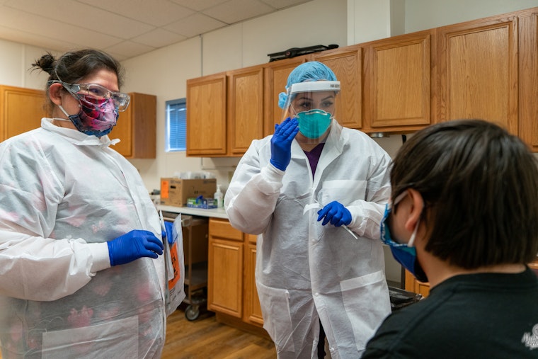Nurses conduct COVID-19 tests at a clinic in Rapid City, South Dakota, on June 20, 2020. The testing event was run by the Great Plains Tribal Leaders’ Health Board and was made possible through a grant from the Open Society Foundations via a fiscal sponsor, which helped facilitate rapid funding to meet urgent needs. © Arlo Iron Cloud for Return to Heart Foundation/Open Society Foundations Two nurses wearing face masks treat a patient
