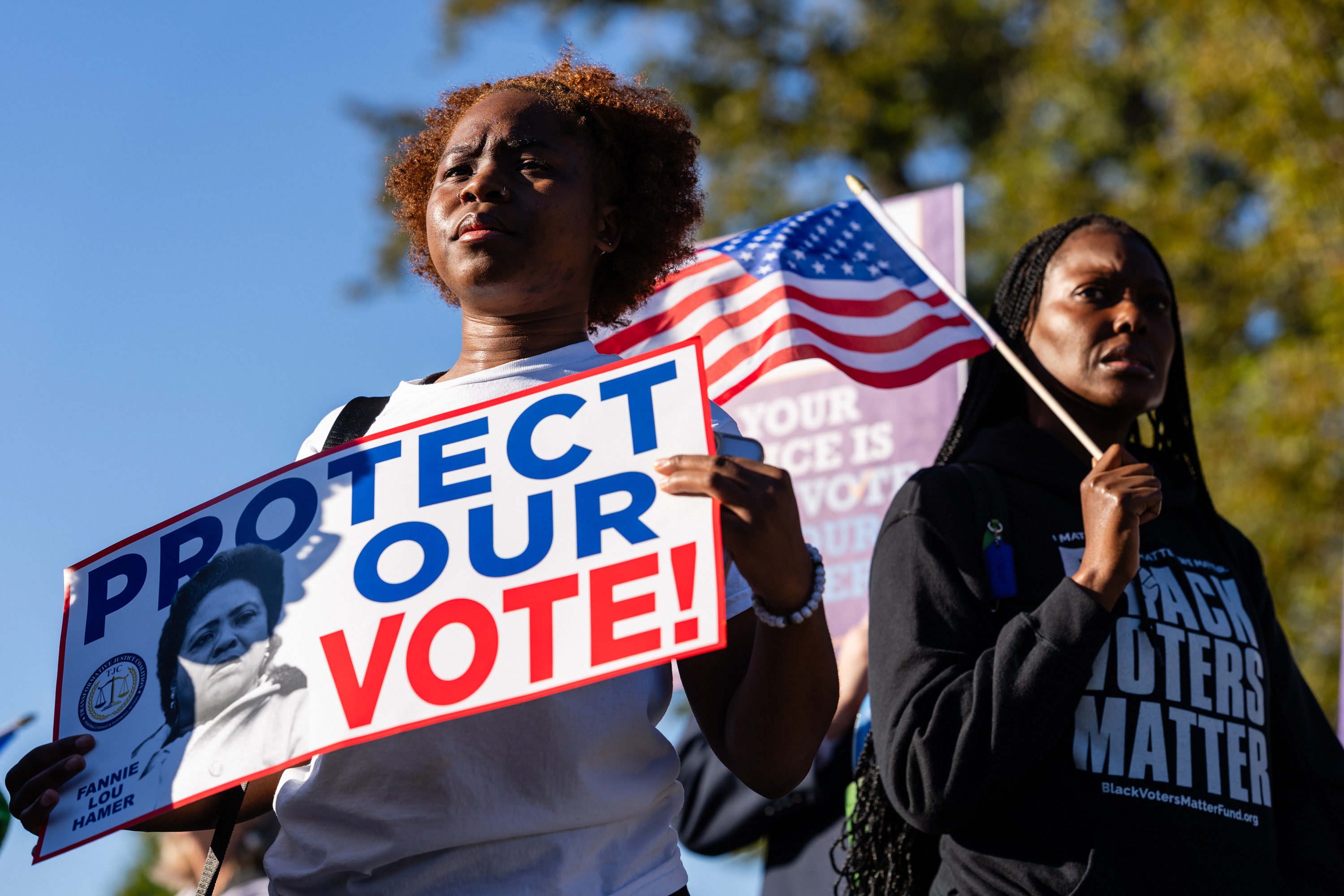 Woman holding a sign that says Protect Our Vote