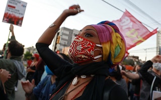 A woman wearing a mask with a raised arm at a protest