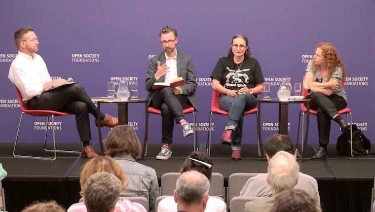 Four people sitting on a stage in front of an audience