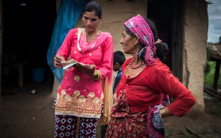 A woman discusses her citizenship status with a paralegal activist, in Kanchanpur District, Nepal, on August 4, 2018. Photo credit: © Kishor Sharma/Majority World for the Open Society Foundations Two women speaking outside a house