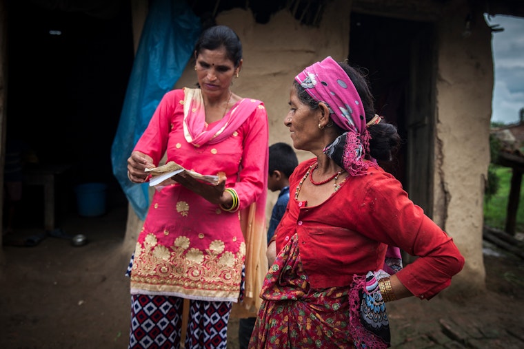 Two women speaking outside a house