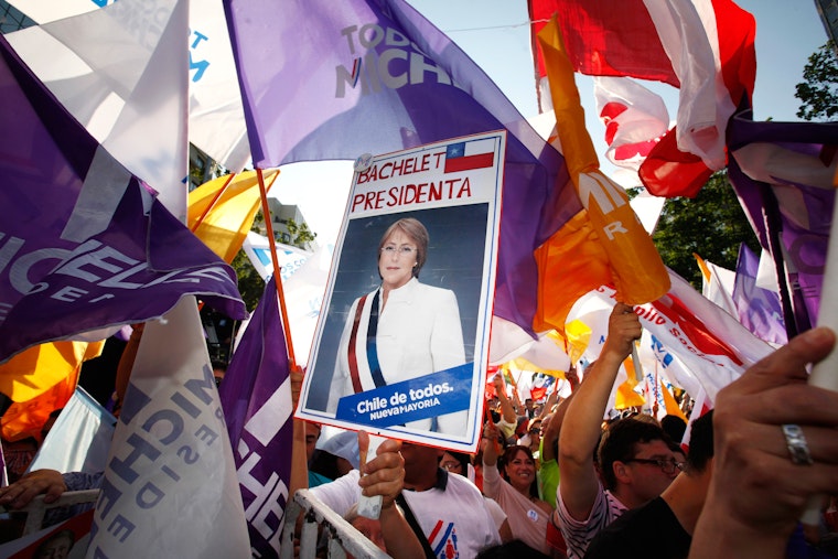 Supporters of Chilean President Michelle Bachelet wave flags during her re-election campaign in Santiago on December 15, 2013. Photo credit: © Jorge Saenz/AP