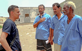 A reporter on left speaks to three men in blue shirts