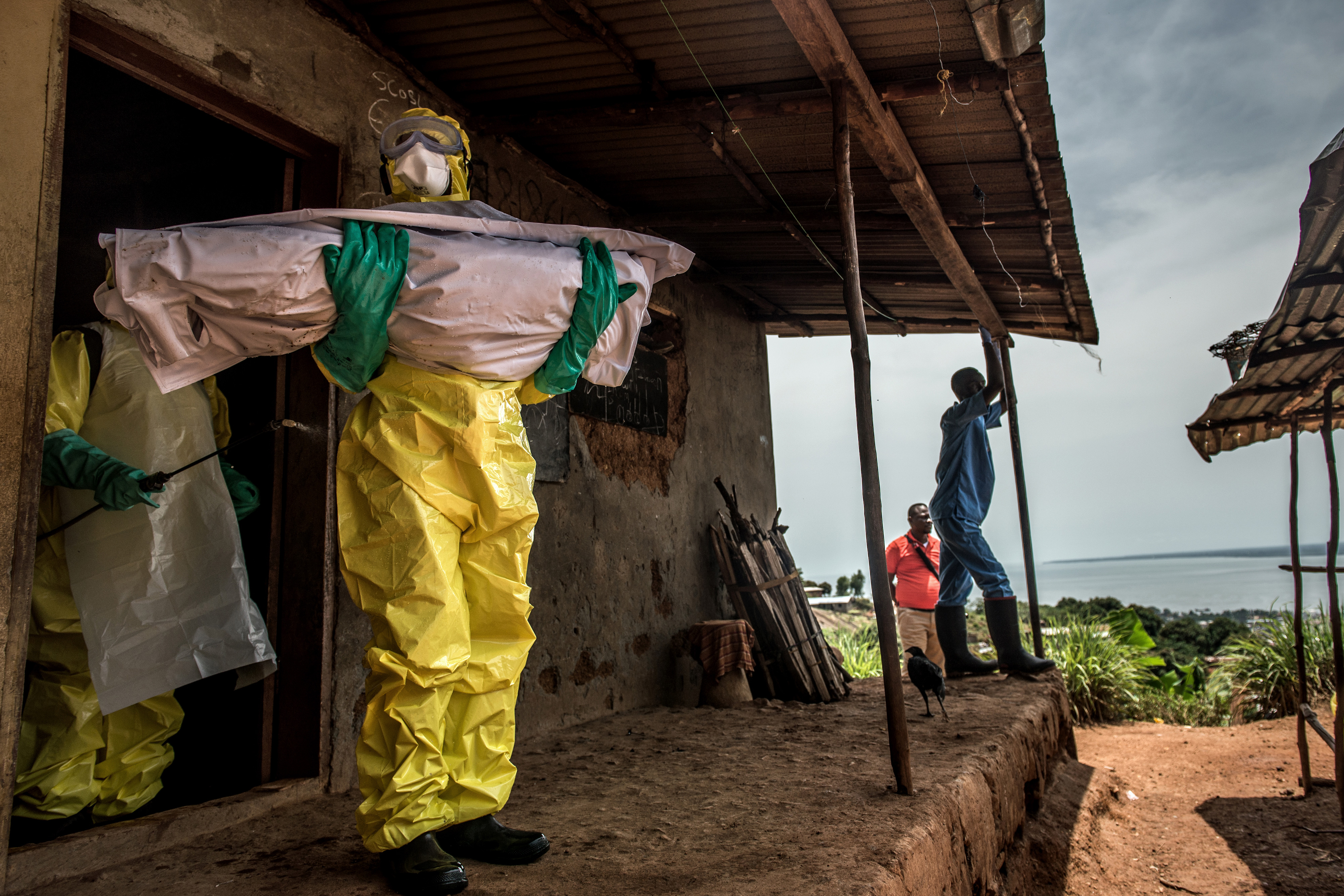 Workers carrying a body out of a home