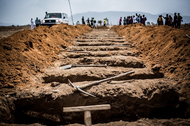 At Waterloo Cemetery in Freetown, Sierra Leone, people dig gravesites in preparation for the day’s burials. During the Ebola outbreak, up to 75 people were buried in the cemetery each day. Both Christian and Muslim ceremonies were held there, and families were allowed to observe from a safe distance.	Photo credit: © Michael Duff Rows of newly dug graves