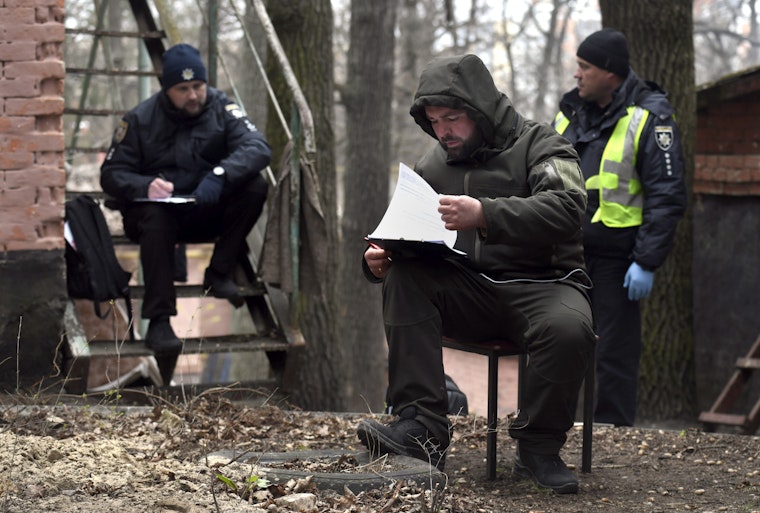 Three people outdoors, reviewing paperwork on a clipboard