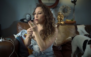 Still image from "The Costs of Criminalizing Sex Work" of a woman putting on make up