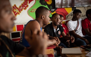 Members of Colectivo Elegua, a grantee of the Open Society Foundations, discuss their programs that educate communities about their rights and counter violence through artistic, cultural, and social activities, in Buenaventura, Colombia, February 16, 2023.© Jair Coll for the Open Society Foundations Men sitting together at a table and having a lively conversation.