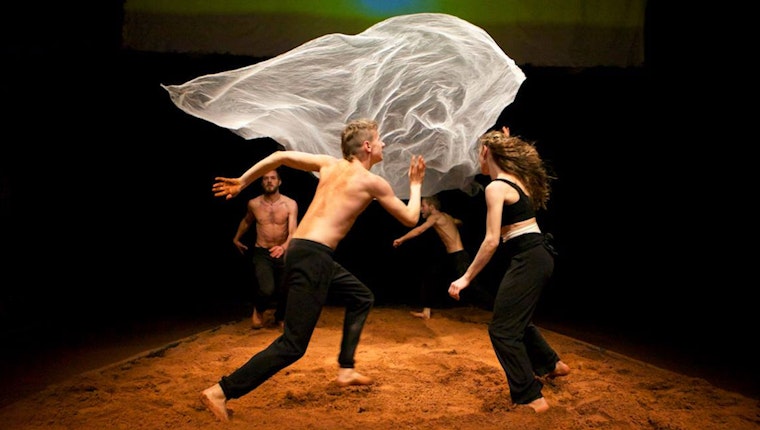 Four performers around a floating sheet