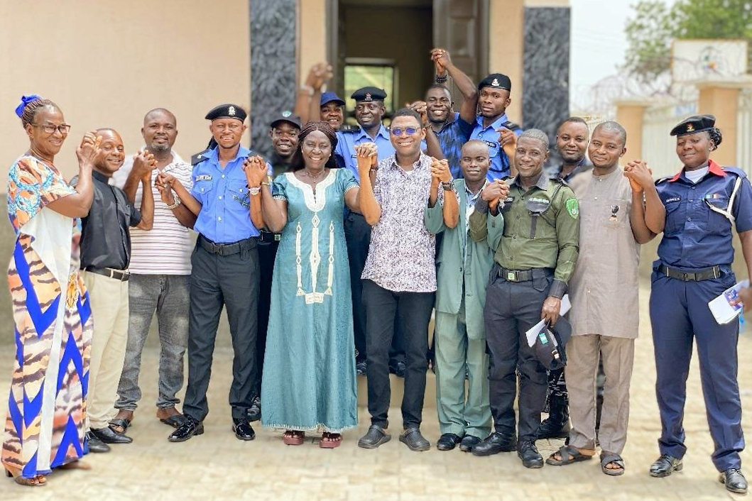 A group of people stand in front of a building holding hands