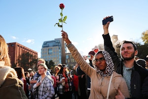 A woman holding a rose in the air at a demonstration