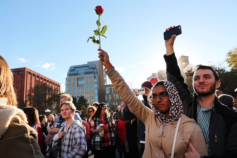 A woman holding a rose in the air at a demonstration