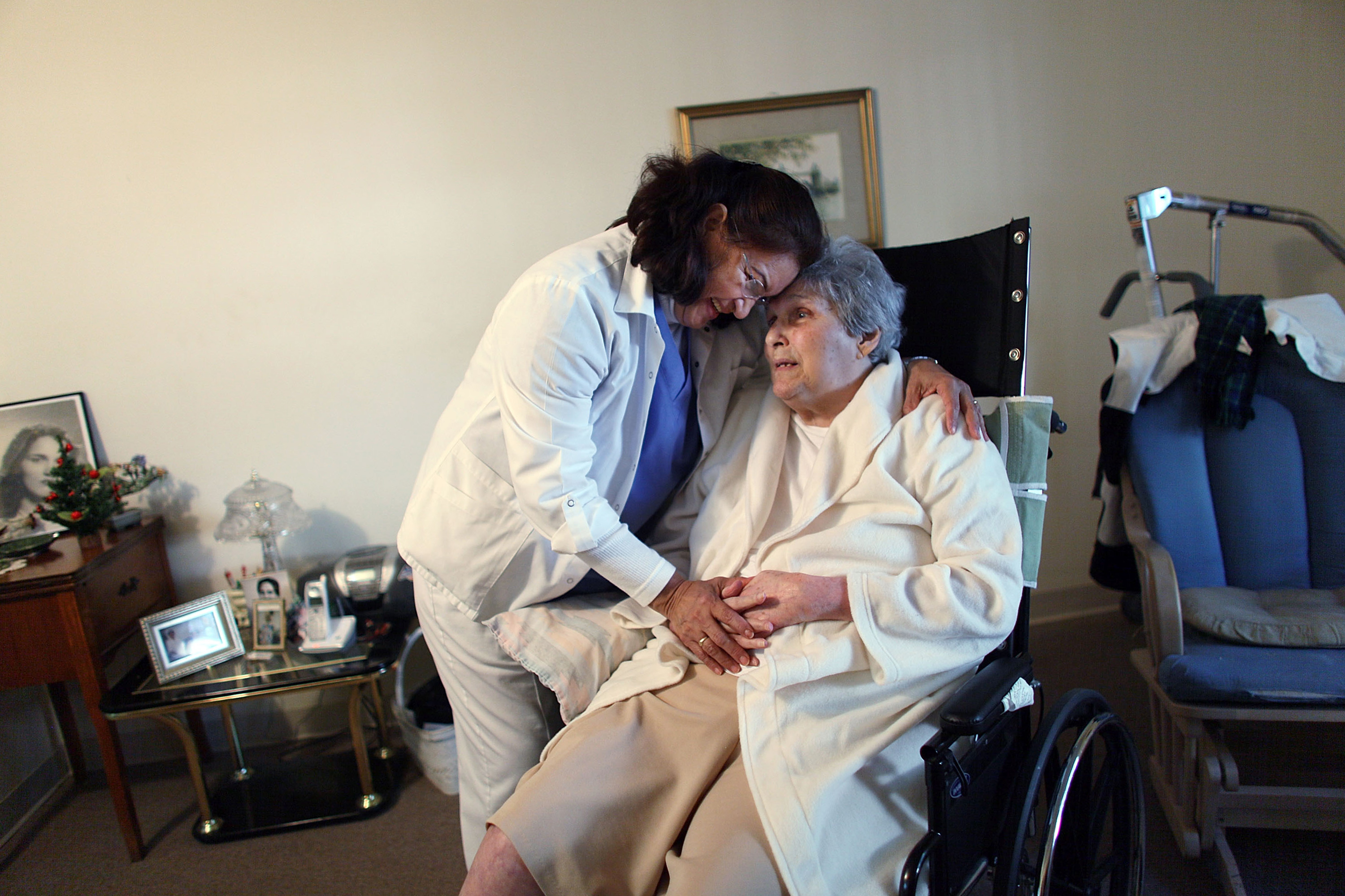 A nurse embracing a patient in a wheelchair