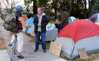 Two people speaking in front of camping tents