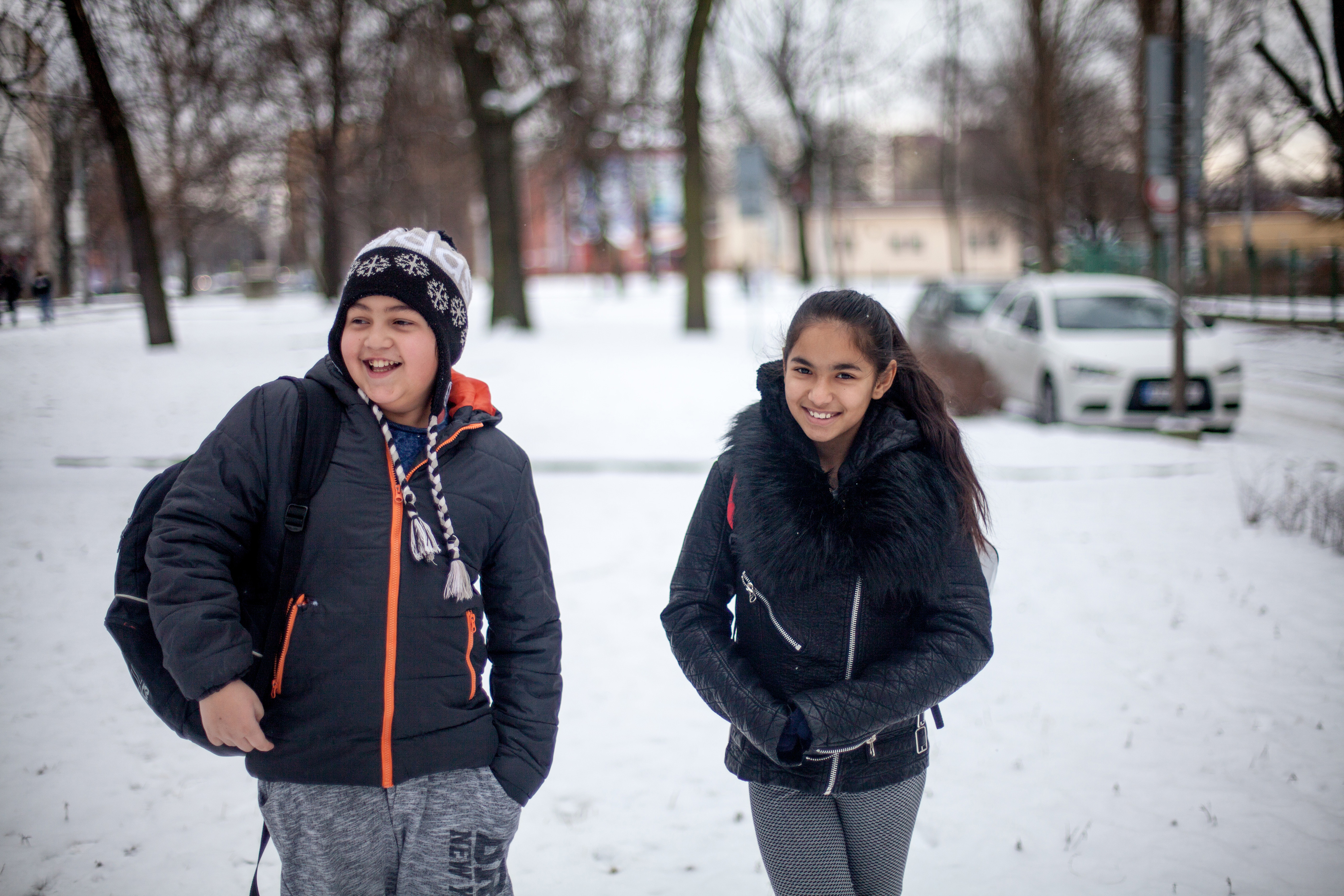 Two friends laughing in the snow on the way to school