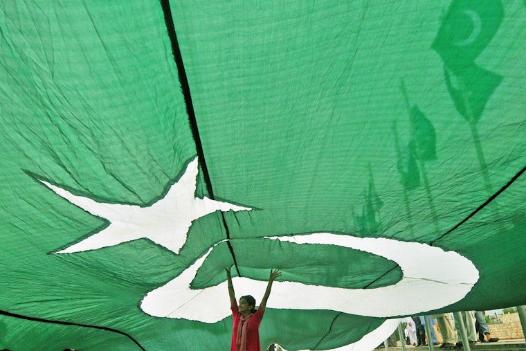 A Pakistani girl stands under the national flag at the Minar-e-Pakistan, the historic monument for the struggle for independence. Photo credit: © Arif Ali/Getty