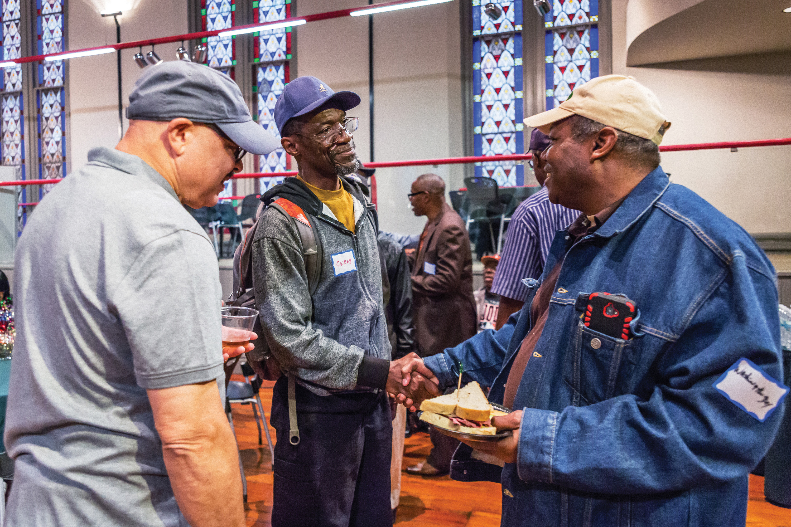 Men shaking hands in greeting in a church meeting hall.