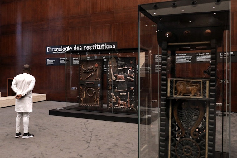 Royal art, that was looted by the French colonial soldiers and recently returned to Benin, seen on display at the Marina Palace of Cotonou in Benin, on July 27, 2022. © Lemouton Stephane/Pool/ABACA Man viewing a glass case of objects
