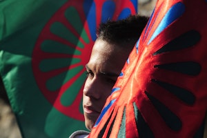 A young boy holds a Roma flag during a demonstration in the northeastern town of Miskolc, Hungary, on October 17, 2012. Photo credit: © Attila Kisbenedek/AFP/Getty A boy between two flags