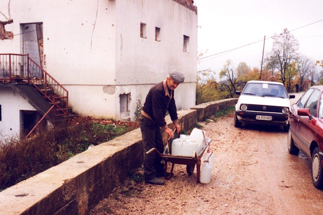 An elderly man stacking bottles of water on a cart