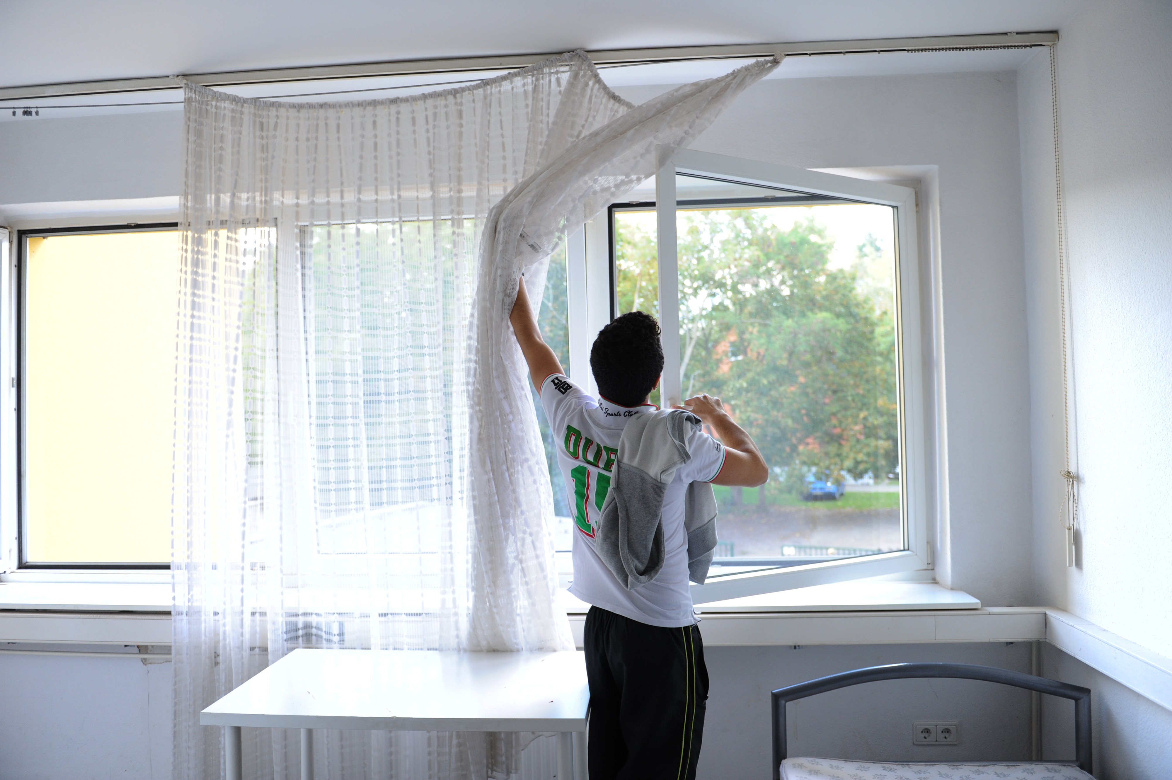 A young man opening a window