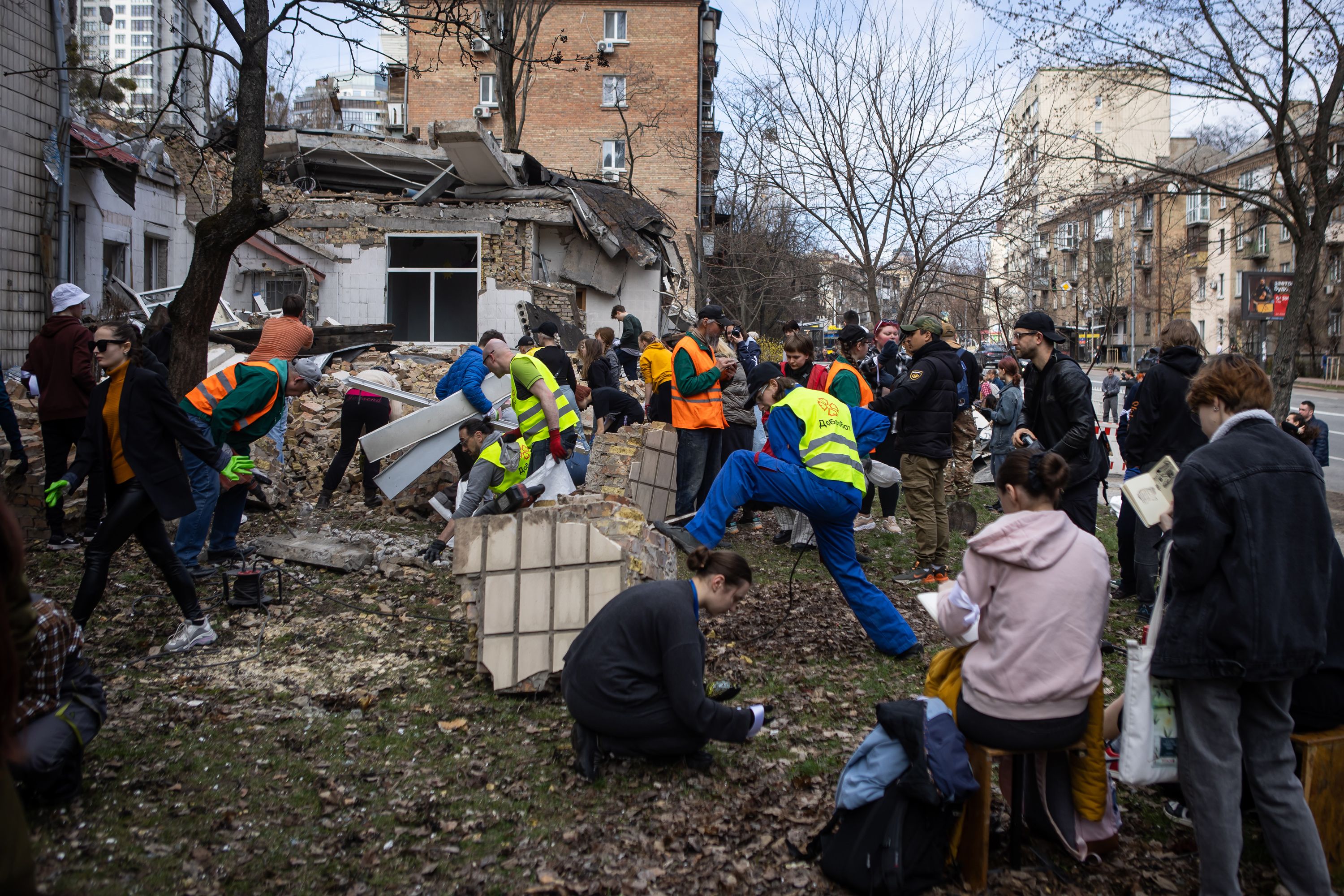 A group of people pick up debris after a missile attack