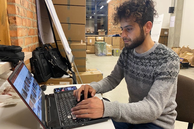 A person working on a laptop with boxes in the background