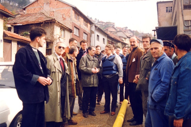 George Soros with a group of people looking at a water main