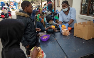 Kids being handed food at a soup kitchen table