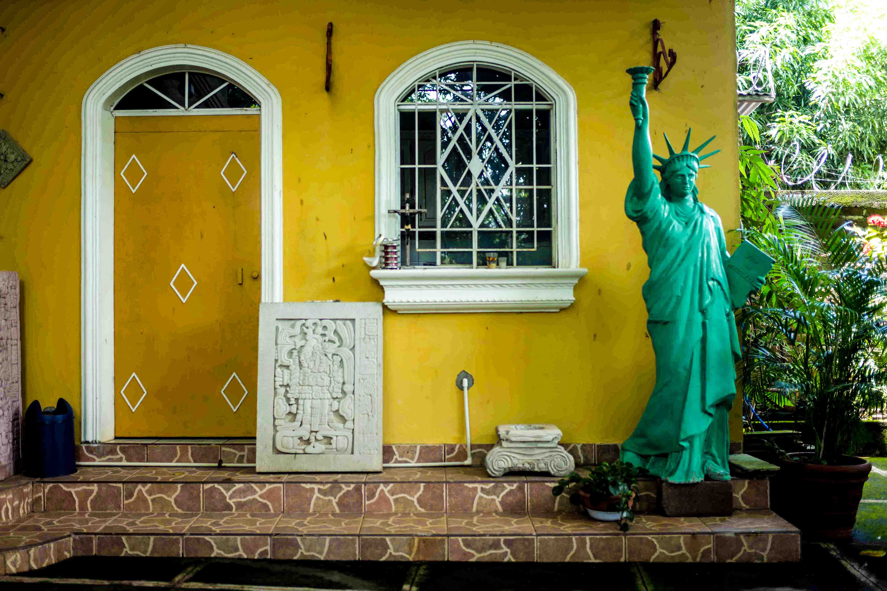 A statue in front of a yellow house