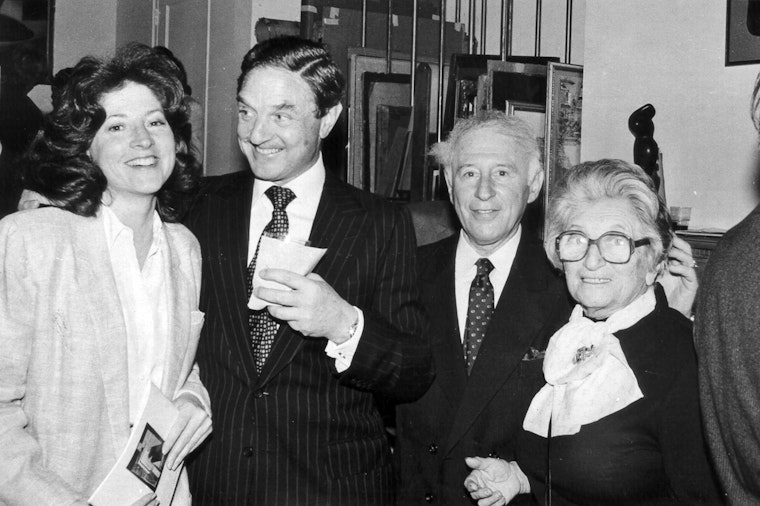 George Soros (second from left) and his mother Erzebet (right), at a Hungarian art exhibition reception in New York in 1983. A group of four people stand joyfully at a party