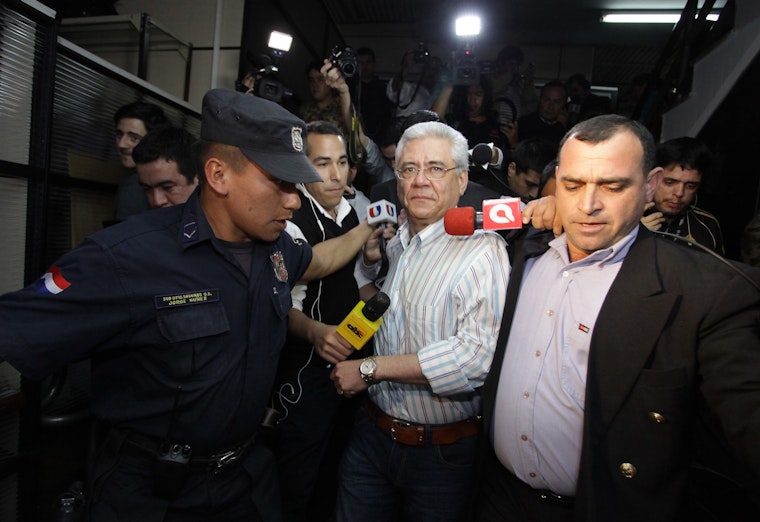 The rector of the National University of Asunción on September 25, 2015, shortly after he resigned amid accusations of corruption. Photo credit: © Stringer/Getty Police escorting a man followed by photographers