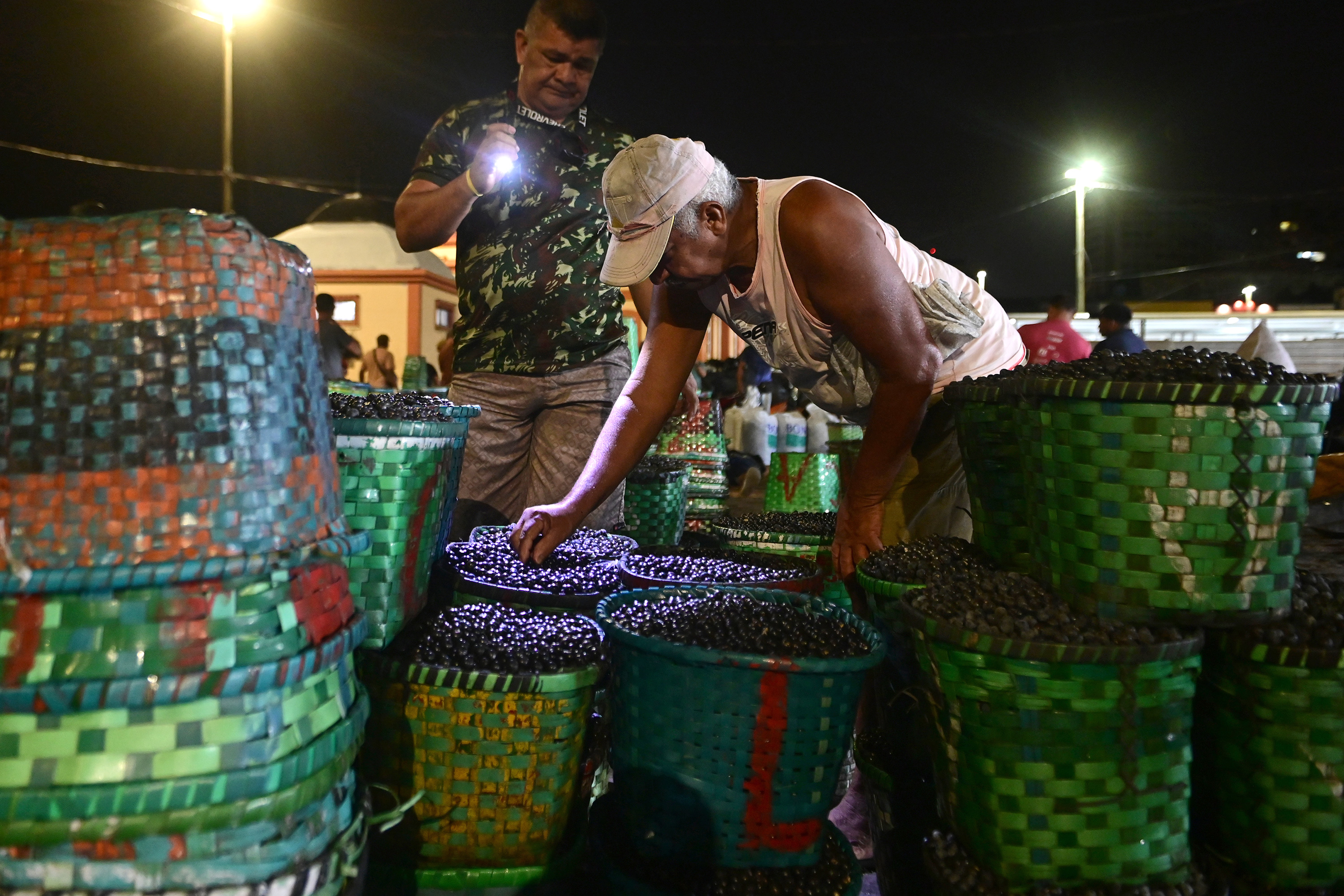 A man checks on the quality of acai berries at a market