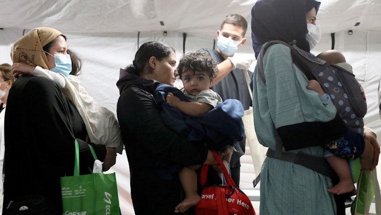 A woman standing in line with other women and holding a baby