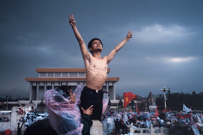 A shirtless man reaching into the air