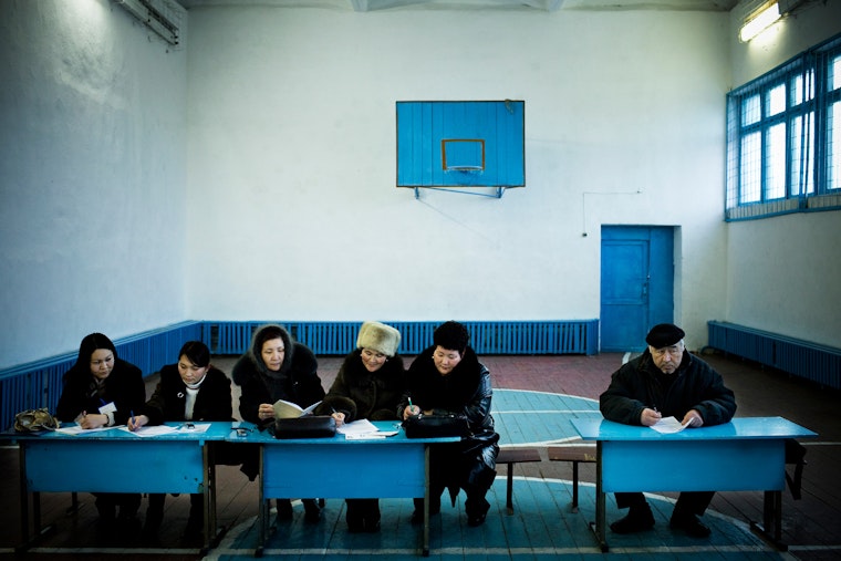 People seated at school desks in gymnasium